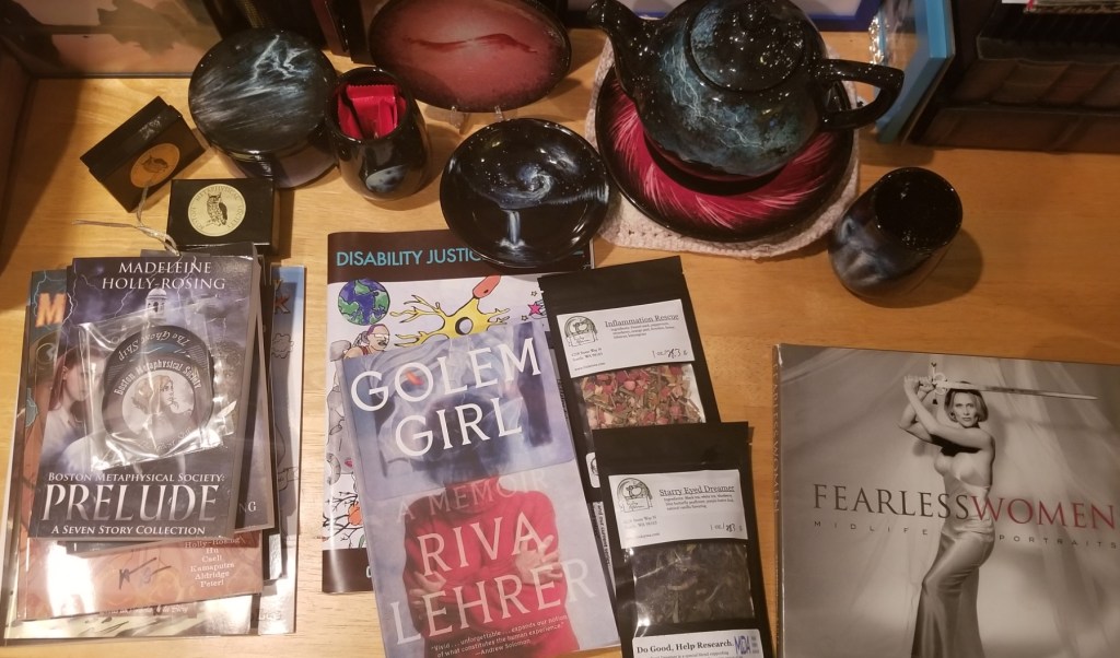 On a coffee table: a collection of books, two bags of loose leaf tea, and assorted ceramics