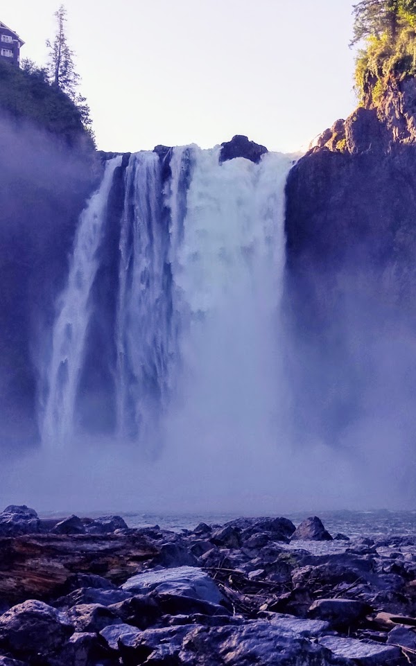 Snoqualmie Falls, a 268 foot tall waterfall crashing down, continuing in the Snoqualmie River