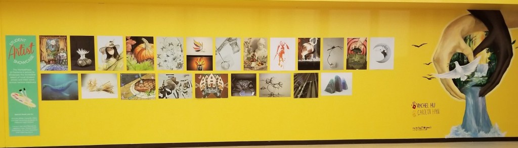 A yellow wall with a collage of different students' paintings and photographs. At the end of the image - two hands, one light, one dark, forming a heart that has a dove flying out and water falling down.